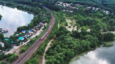 Bir tren kırsalda demiryolu boyunca ilerliyor.