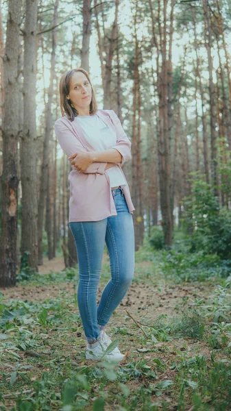 Mujer joven delgada en el bosque verde. Anillo de madera de árbol y mujer pensativa de pie en el bosque mirando hacia arriba — Foto de Stock