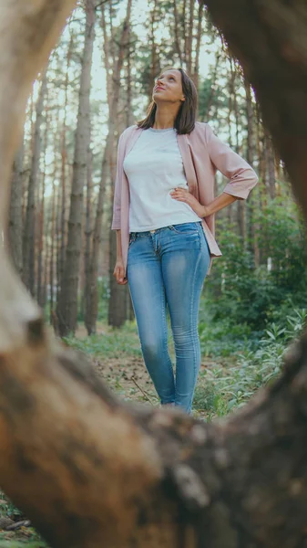 Jovem magro na floresta verde. Anel de madeira de árvore e mulher pensativa em pé na floresta olhando para cima — Fotografia de Stock