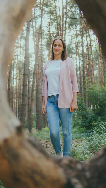 Giovane donna magra nella foresta verde. Anello di legno da albero e donna premurosa in piedi nella foresta guardando in alto — Foto Stock