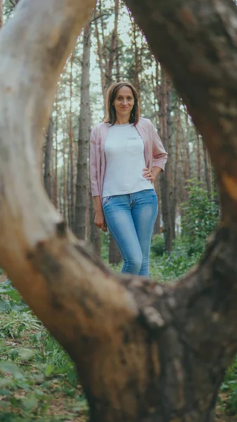 Slim young woman in green forest. Wooden ring from tree and thoughtful woman standing in forest looking up — Stock Photo, Image