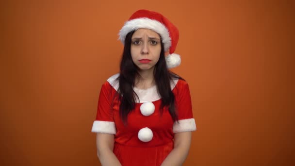 Красивая молодая женщина в костюме Санта-Клауса держит коробку с подарками на оранжевом фоне. С Новым годом и Рождеством!. — стоковое видео