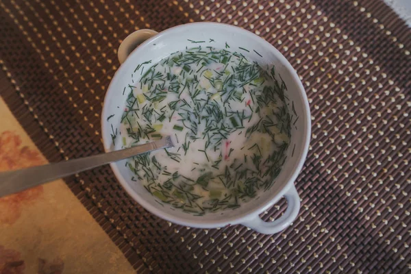 Nombre de sopa fría - okroshka, el plato nacional de la cocina de Rusia y Ucrania. Sopa fría con pepinos frescos, rábanos, patata y salchicha con yogur en tazón.. — Foto de Stock