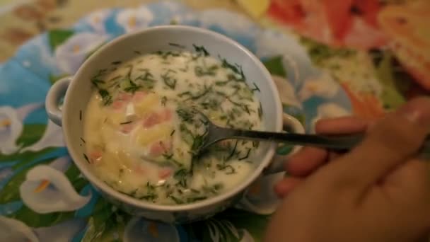 Kalter Suppenname - okroshka, das Nationalgericht der Küche Russlands und der Ukraine. Kalte Suppe mit frischen Gurken, Radieschen, Kartoffeln und Wurst mit Joghurt in Schüssel. — Stockvideo