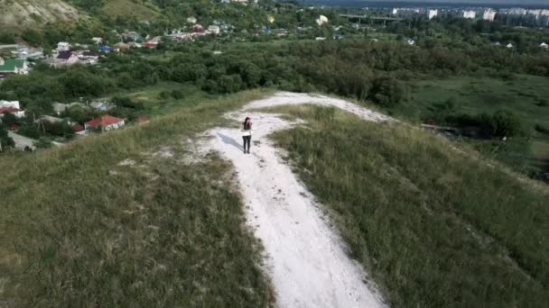 Resande kvinna med karta i naturen. Kvinna med ryggsäck går i smal slingrande stig går genom gröna buskar och träd. Tillfällig kvinna som bär ryggsäck. Resenär som reser ensam — Stockvideo