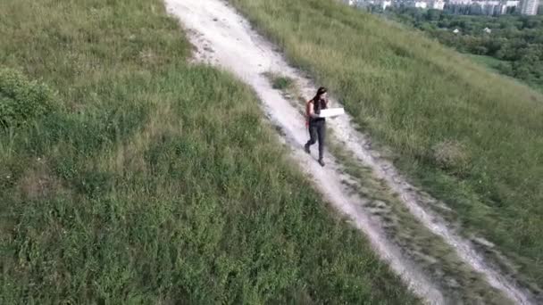 Mulher viajando com mapa na natureza. Mulher com mochila andando em caminho sinuoso estreito passando por arbustos verdes e árvores. Mulher casual carregando mochila. Viajante viajando sozinho — Vídeo de Stock