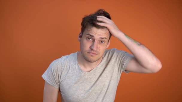 Sabah uykulu bir adam, saçını tarıyor turuncu bir arka planda. — Stok video