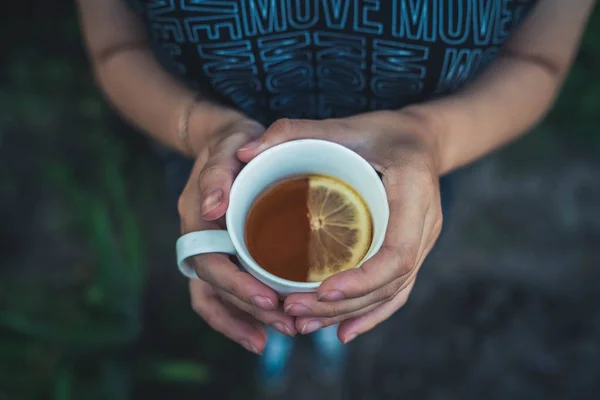 Flickan håller en kopp te med citron. Kvinna i kallt sommar te dricka te på gatan. — Stockfoto