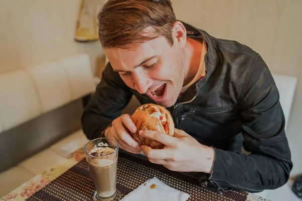 快乐的人在吃快餐汉堡包一个男人坐在桌旁吃着芝士汉堡 — 图库照片