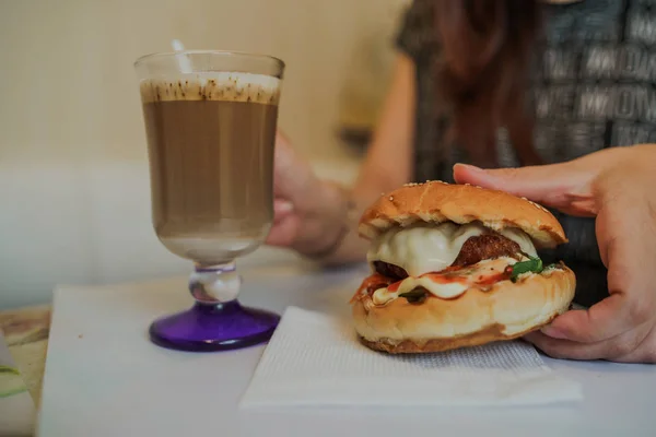 Frauenhände halten frische leckere Burger in der Hand. Köstlicher Hamburger in den Händen. Fastfood-Essen. — Stockfoto