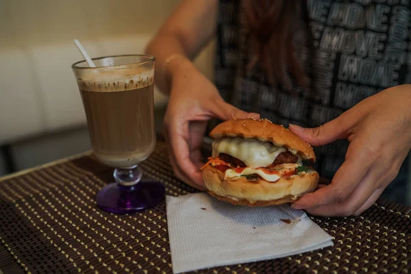 Frauenhände halten frische leckere Burger in der Hand. Köstlicher Hamburger in den Händen. Fastfood-Essen. — Stockfoto