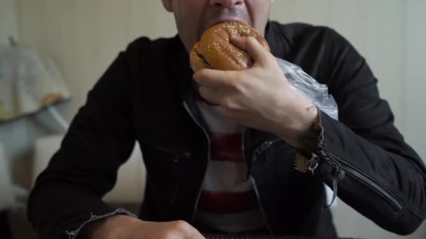 Jovem Está Comendo Hambúrguer Homem Está Sentado Mesa Comendo Cheeseburger — Vídeo de Stock