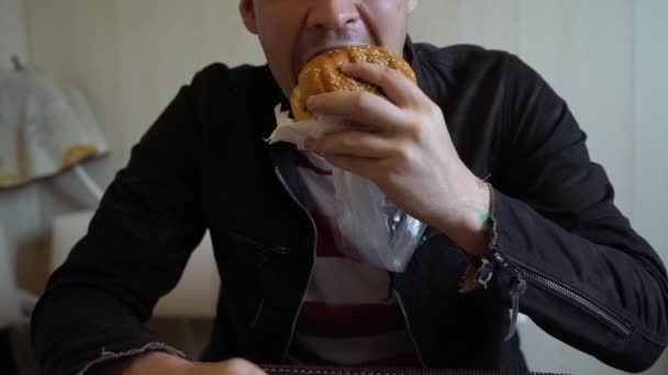 Joven Está Comiendo Hamburguesas Hombre Está Sentado Mesa Comiendo Queseburger — Vídeos de Stock