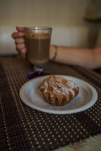 Горячий кофе с вкусным кексом в тарелке на столе в кафе быстрого питания. — стоковое фото