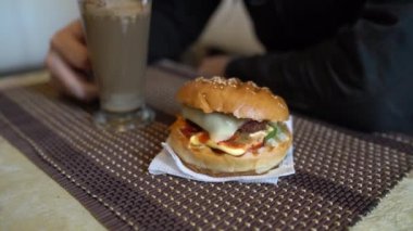 Yemek fotoğrafçılığı. Fast food Cafe 'deki masada hamburgerli sıcak kapuçino.