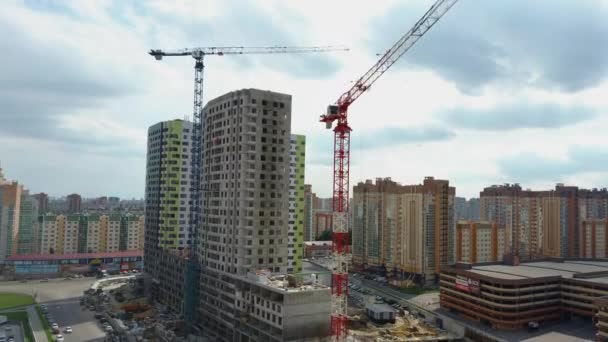 Vinç ve bina yapım aşamasında. İnşaat alanı. Bulutlu gökyüzüne karşı inşaat halindeki vinçler ve yüksek binalar — Stok video