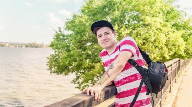 Güneşli bir günde nehir kenarında bir portre adam. Deniz kenarında poz veren güzel bir adam.