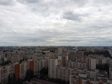 Bulutlu günlerde büyüyen şehrin havadan görünüşü. Şehir merkezindeki bulutlu gökyüzü altında evleri ve yolları olan yeni binaların insansız hava aracı görüntüsü
