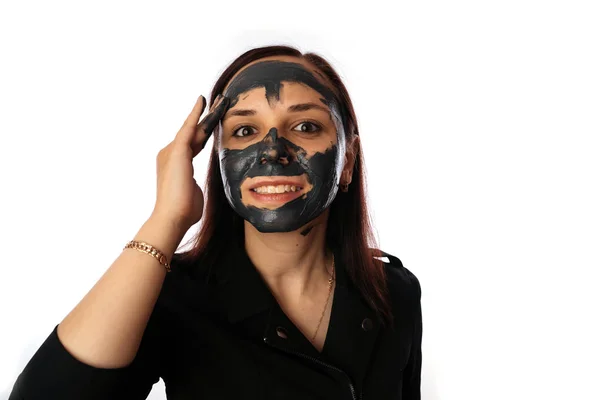 Egy fiatal nő fekete maszkot rak az arcra, fehér háttérrel elszigetelve. Az egészséges életmód, szépség, testápolás fogalma. — Stock Fotó