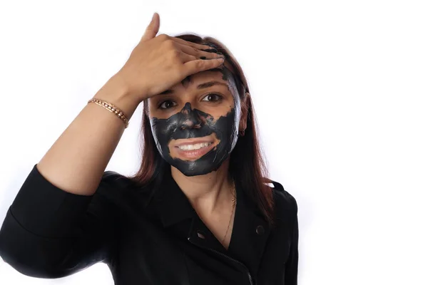 Молодая женщина наносит черную маску на лицо изолированы на белом фоне. Концепция здорового образа жизни, красоты, ухода за телом . — стоковое фото