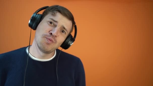Junger Mann Mit Kopfhörer Und Ohren Singt Auf Orangefarbenem Hintergrund — Stockvideo