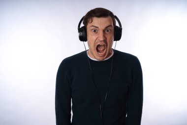 Kulaklıklı genç adam beyaz arka planda yalnız dans ediyor. Uluslararası Müzik Günü konsepti.