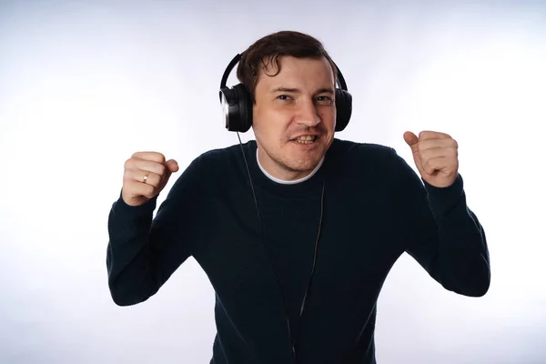 Hermoso hombre joven en los auriculares está bailando aislado en el fondo blanco. El concepto del Día Internacional de la Música. — Foto de Stock