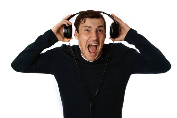 Hermoso hombre joven en los auriculares está bailando aislado en el fondo blanco. El concepto del Día Internacional de la Música. — Foto de Stock