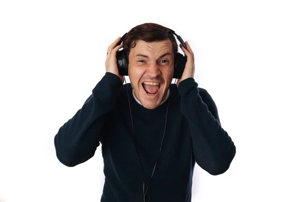 Hermoso hombre joven en los auriculares está bailando aislado en el fondo blanco. El concepto del Día Internacional de la Música. — Foto de Stock