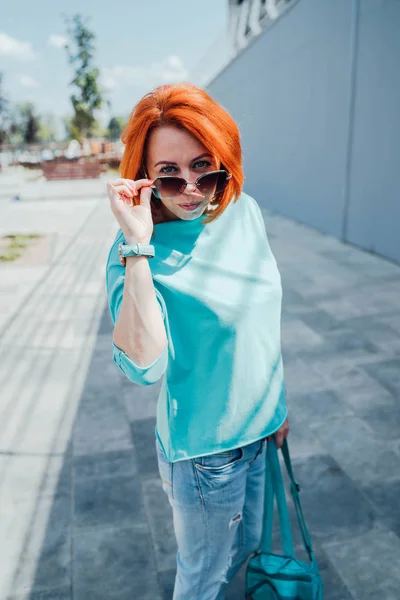 Retrato de jovem ruiva em roupas casuais e com óculos de sol . — Fotografia de Stock
