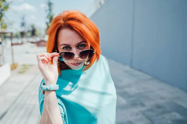 Retrato de jovem ruiva em roupas casuais e com óculos de sol . — Fotografia de Stock