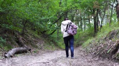 Parkta yürüyen isimsiz bir kadın. Süslü sırt çantalı genç bir bayanın arka görüntüsü. Sessiz sonbahar parkında yol boyunca yürüyor.