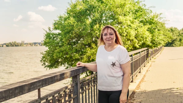 Una guapa jovencita vestida con ropa casual paseando por el paseo marítimo cerca del agua. — Foto de Stock