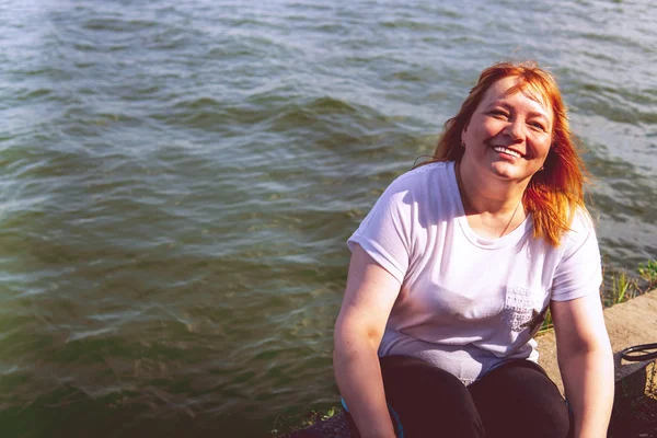 El retrato de una bella mujer sonriente se encuentra en el frente del mar, cerca del agua.. — Foto de Stock