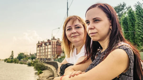 Duas mulheres jovens em roupas de rua estão andando na orla ao longo da água. — Fotografia de Stock