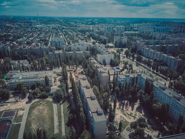 Aerial view of growing city in sunlight. Drone view of new building complex in city center with houses and roads under cloudy sky — Stock Photo, Image