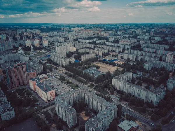 Flygfoto över växande stad i solljus. Drönare syn på ny byggnad komplex i centrum med hus och vägar under molnig himmel — Stockfoto