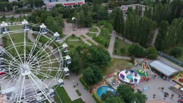 公園の空中ビュー。観覧車が公園にある。公園はレクリエーションのために作成された景観エリアです。それは人々のための楽しい娯楽の場所です。. — ストック動画