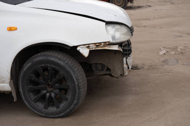 Buruşuk kapüşonlu ve tamponlu bir araba. Asfaltlı park yerine park etmiş buruşuk metal şapkalı eski bir araba.