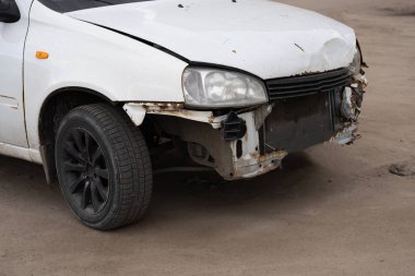 Buruşuk kapüşonlu ve tamponlu bir araba. Asfaltlı park yerine park etmiş buruşuk metal şapkalı eski bir araba.