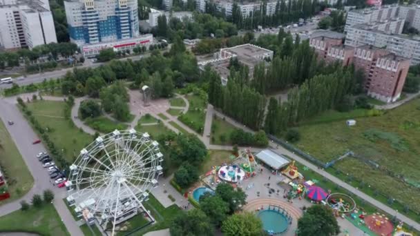 公園の空中ビュー。観覧車が公園にある。公園はレクリエーションのために作成された景観エリアです。それは人々のための楽しい娯楽の場所です。. — ストック動画