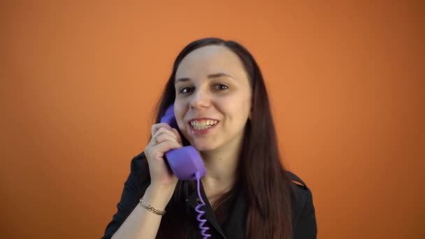 オレンジ色の背景で電話で話す女性 — ストック動画
