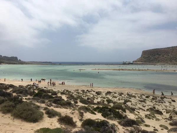 Una hermosa playa de Balos en la isla de Creta en Grecia en un clima nublado. Los turistas se relajan y se bañan en aguas cristalinas de la playa de Balos. Concepto: turismo y viajes . — Foto de Stock
