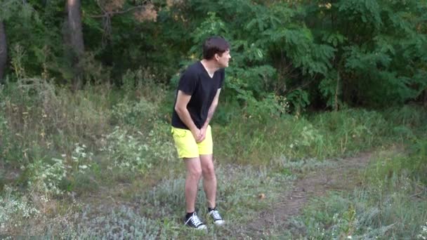 Un joven guapo está sufriendo la necesidad de pegar en el bosque.. — Vídeos de Stock