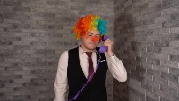Le directeur crie à noirci au téléphone. Travailleur de bureau en wig clown, concept de clown au travail. Homme d'affaires avec perruque clown. Un client insatisfait se plaint au téléphone. — Video