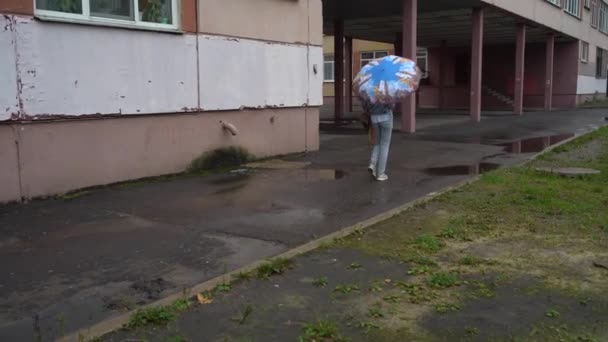 Ένα κορίτσι με ομπρέλα περπατά στην πόλη μια συννεφιασμένη και βροχερή μέρα — Αρχείο Βίντεο