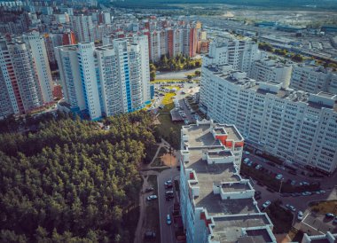 Modern konut binalarının havadan görünüşü. Yüksek katlı binaların dış cephesi. Ağaçlarla çevrili konut binası. Orman çevresindeki gökdelenler