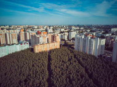 Modern konut binalarının havadan görünüşü. Yüksek katlı binaların dış cephesi. Ağaçlarla çevrili konut binası. Orman çevresindeki gökdelenler