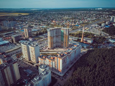 Modern konut binalarının havadan görünüşü. Yüksek katlı binaların dış cephesi. Ağaçlarla çevrili konut binası. Orman çevresindeki gökdelenler