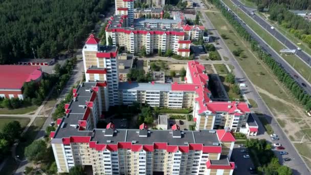 Vista aérea de la ciudad en crecimiento a la luz del sol. Drone vista del nuevo complejo de edificios en el centro de la ciudad con casas y carreteras bajo el cielo nublado — Vídeo de stock